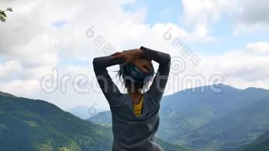 女孩站起来，双臂放在腰间，望着山顶上的地平线。